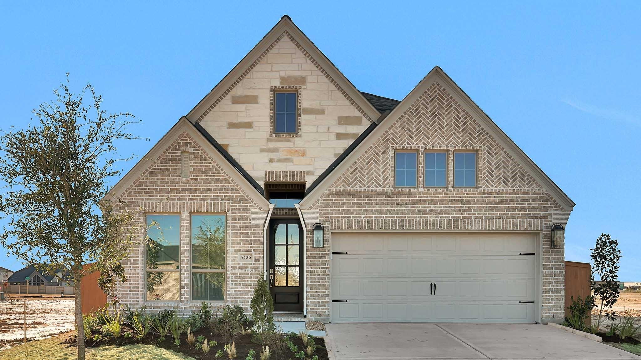 Tan brick new construction home with arched entry in Houston